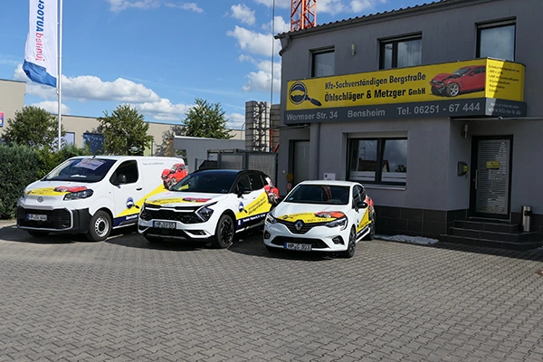 Eingang der Firma mit bedrucktem Firmenauto vor der Tür